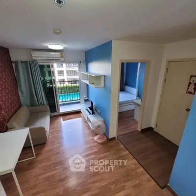 Modern living room with wooden flooring, blue accent wall, and balcony view in a stylish apartment.