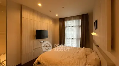 Cozy bedroom with modern decor and wall-mounted TV in a stylish apartment.