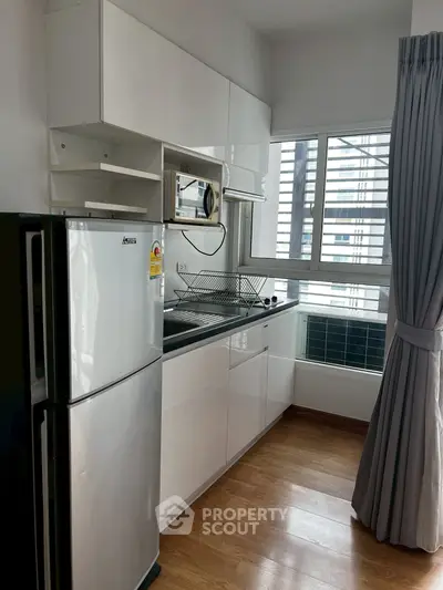 Modern kitchen with sleek cabinets and large window in a high-rise apartment.