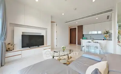 Modern living room with sleek design and open kitchen layout, featuring a large TV and comfortable seating.