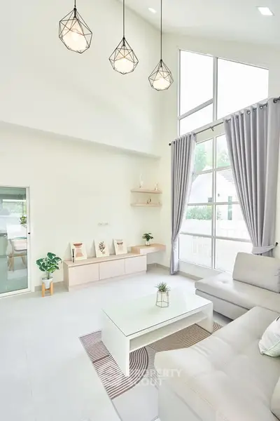 Bright and modern living room with high ceilings and large windows, featuring elegant lighting and minimalist decor.