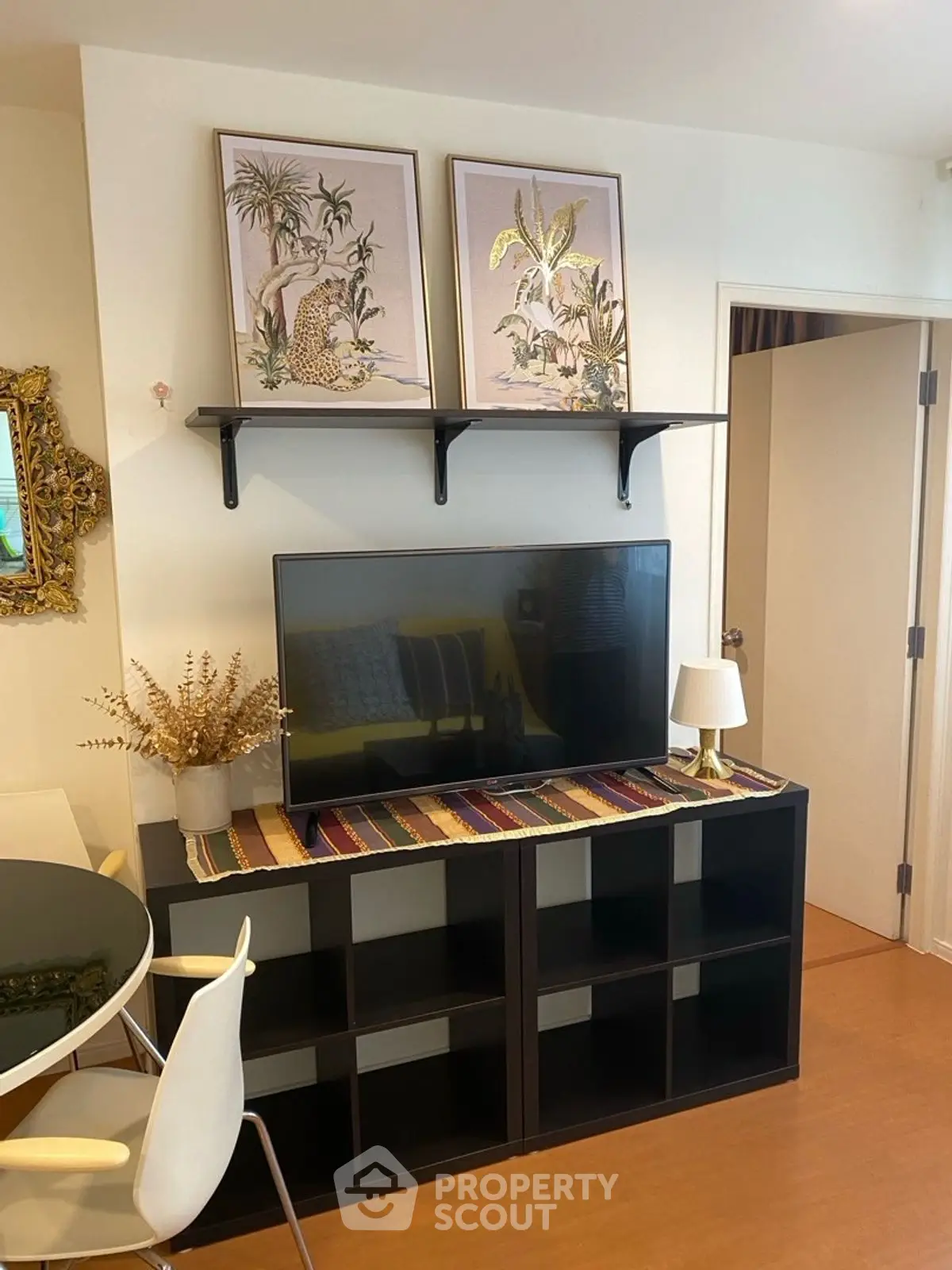 Stylish living room with modern decor, TV on shelf, and elegant wall art.