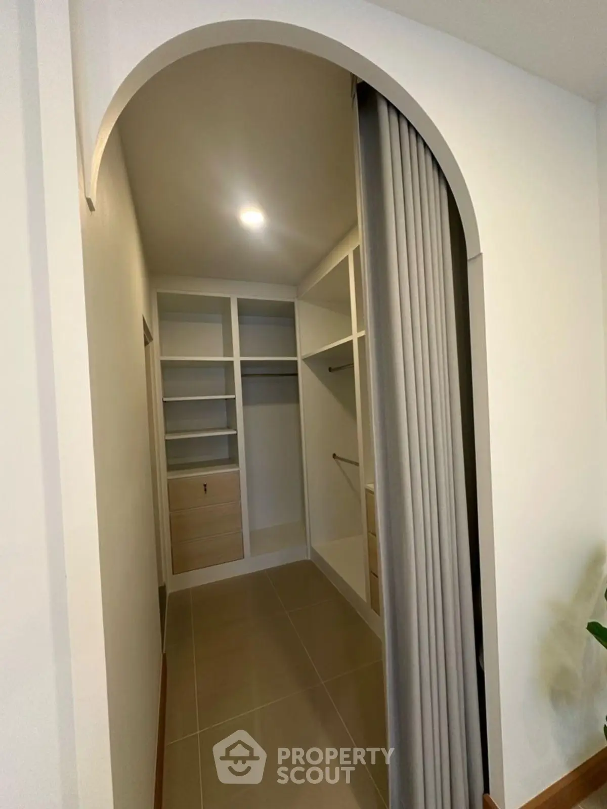 Spacious walk-in closet with modern shelving and elegant archway entrance.