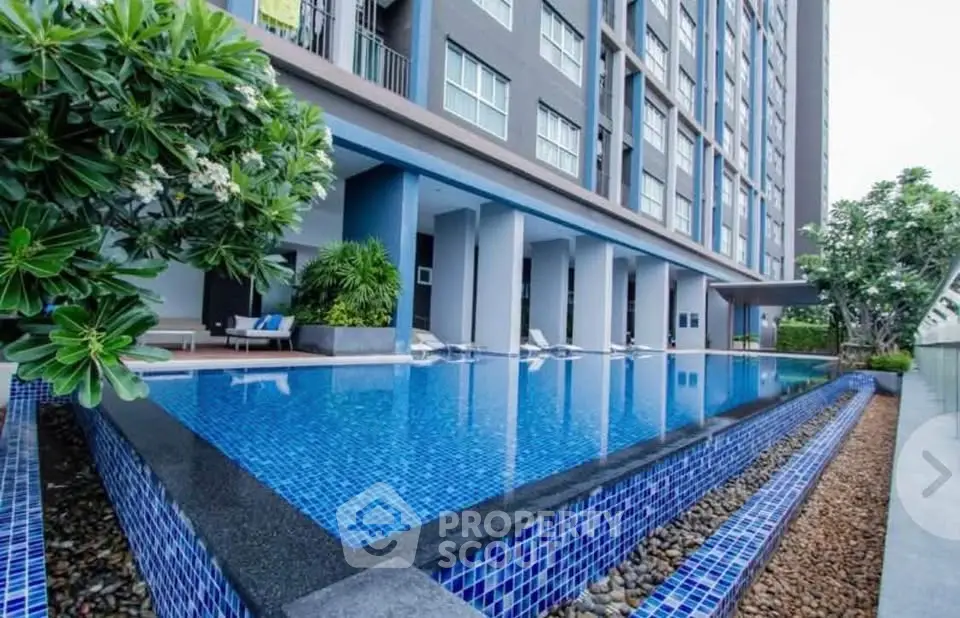 Luxurious modern apartment building with stunning outdoor pool and lush greenery.