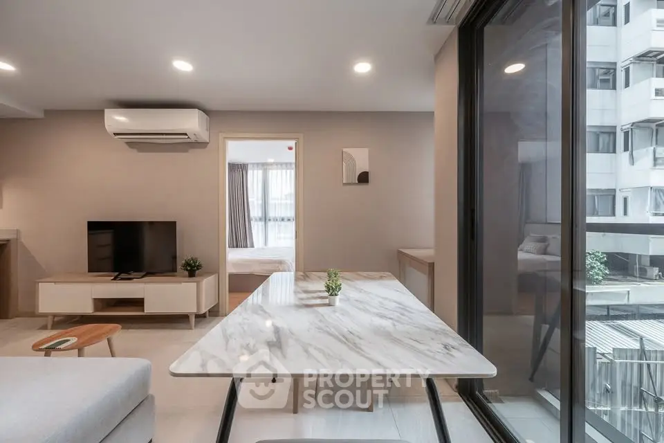 Modern open-plan living room with marble dining table and large windows in urban apartment.