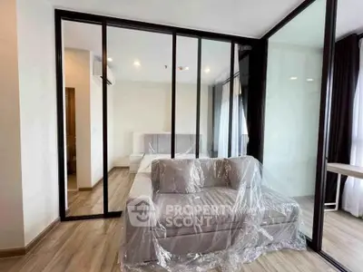 Modern apartment with glass partition, cozy sofa, and elegant bedroom setup.