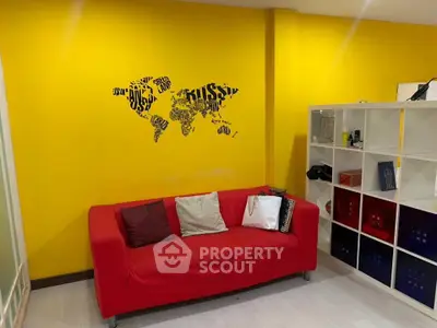 Vibrant living room with red sofa and yellow wall featuring world map art, perfect for modern urban living.