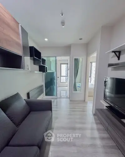 Modern living room with sleek design and large TV, featuring stylish shelving and a cozy sofa.