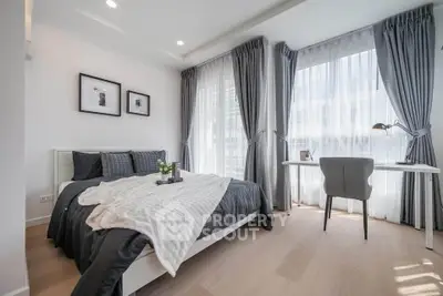 Modern bedroom with stylish decor and natural light, featuring a cozy bed and a sleek desk area.