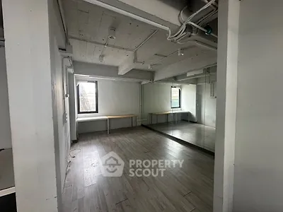 Spacious industrial-style room with large windows and mirrored wall