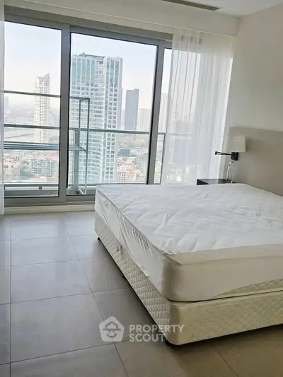 Modern bedroom with stunning city view and large windows in high-rise apartment.