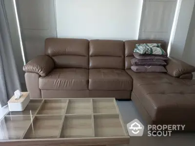 Modern living room with stylish brown leather sofa and glass-top coffee table