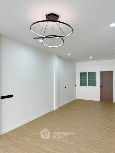 Spacious modern living room with stylish ceiling light and wooden flooring, perfect for contemporary living.