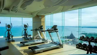 Luxurious high-rise gym with panoramic ocean views and modern fitness equipment.