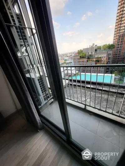 Modern apartment balcony with city view and pool below, ideal urban living.