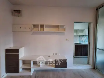 Modern living room with built-in shelves and view into kitchen