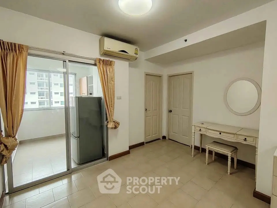 Spacious living area with air conditioning and sliding glass doors leading to a balcony, featuring a stylish vanity.