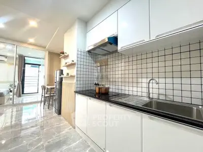 Modern kitchen with sleek white cabinets and tiled backsplash in open layout apartment.