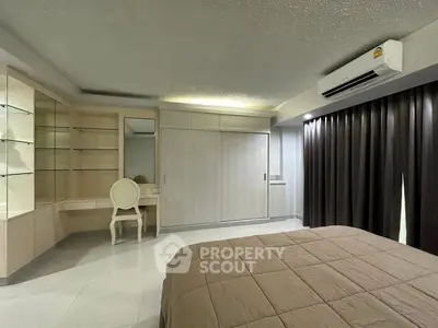 Spacious bedroom with built-in wardrobe and elegant vanity in modern apartment.