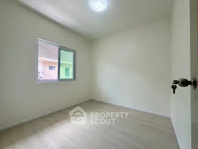 Spacious empty room with window and wooden flooring, ideal for customization.