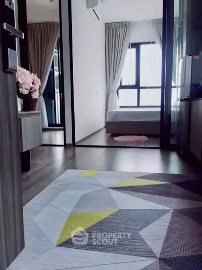 Modern apartment interior with stylish decor and natural light, featuring a cozy bedroom and geometric rug.
