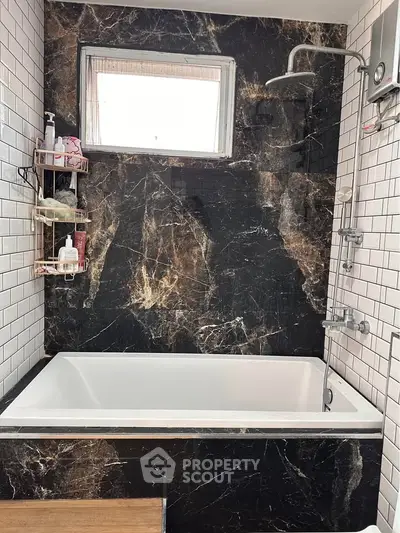 Luxurious bathroom with marble wall and modern bathtub, perfect for relaxation.