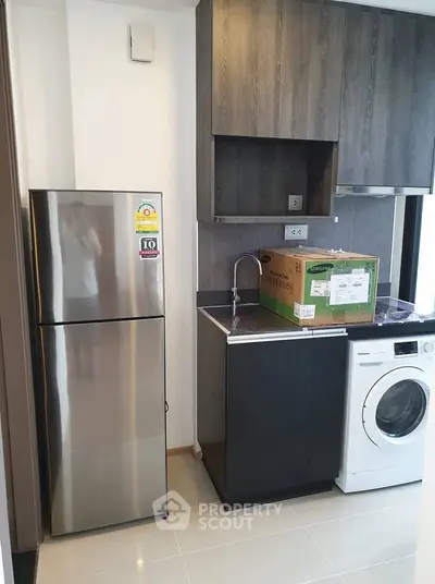 Modern kitchen with stainless steel fridge and washing machine in sleek apartment