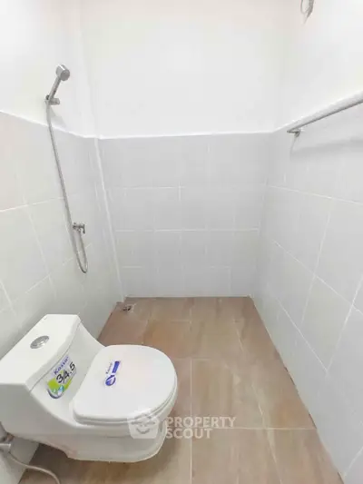 Minimalist bathroom with white tiles and modern fixtures in a real estate property.