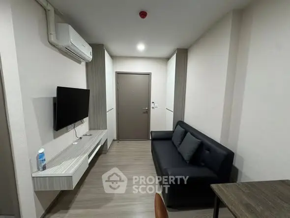 Modern living room with sleek furniture and wall-mounted TV in a cozy apartment.