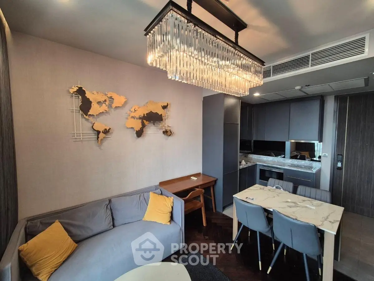 Modern living room with elegant chandelier and stylish kitchen in open layout apartment.