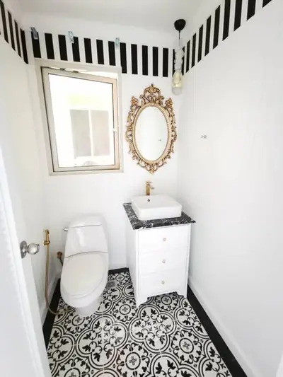Chic black and white bathroom with ornate mirror and patterned floor tiles.