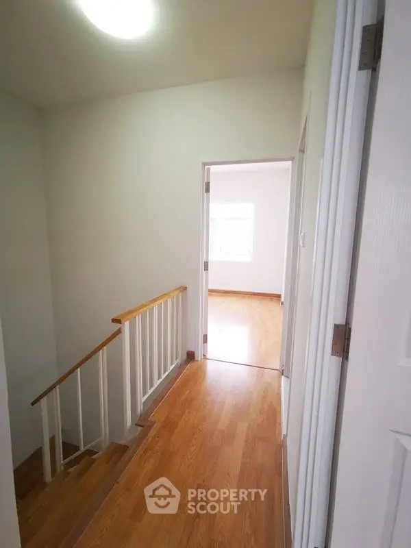 Bright hallway with wooden flooring leading to a sunlit room
