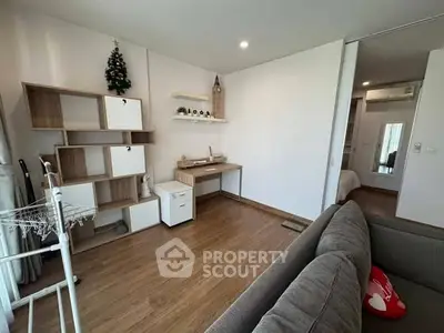 Modern living room with wooden flooring, stylish shelving, and cozy sofa in a bright apartment.