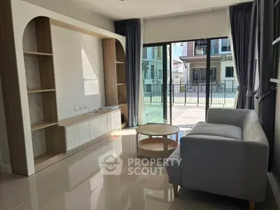 Modern living room with sleek sofa and large windows opening to a spacious balcony.