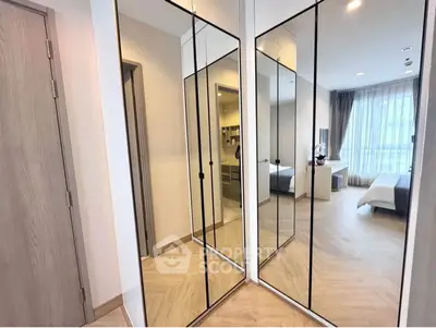 Modern bedroom with mirrored closet doors and large window for natural light.
