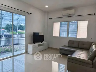 Modern living room with sleek sofa and large windows offering natural light.