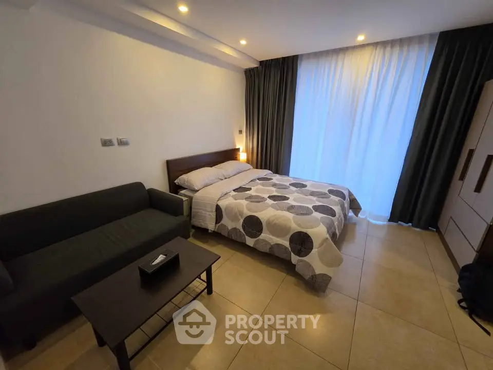 Modern bedroom with cozy bed, stylish sofa, and elegant lighting in a serene setting.