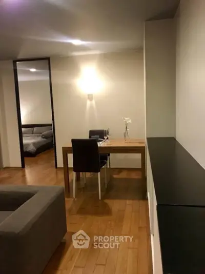 Spacious and modern living area seamlessly connected to a cozy bedroom, featuring warm wooden flooring, elegant furniture, and soft lighting for a welcoming ambiance.