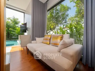 Luxurious living room with pool view and elegant decor, featuring large windows and cozy seating.