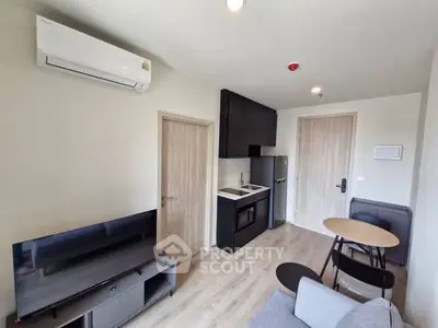 Modern compact living room with kitchenette and air conditioning in a cozy apartment.