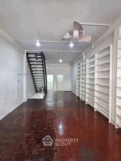 Spacious interior with wooden flooring and built-in shelves, ideal for storage or office setup.
