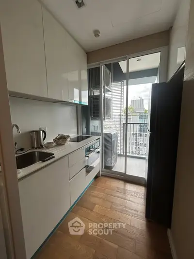 Modern kitchen with sleek cabinetry and balcony access in urban apartment