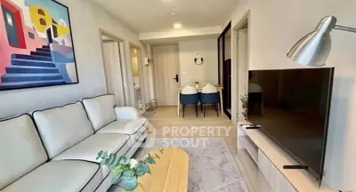 Modern living room with stylish decor and open dining area, featuring a cozy sofa and flat-screen TV.