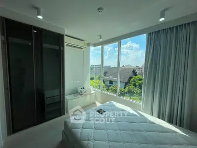 Bright bedroom with large window offering a scenic view, modern furnishings, and ample natural light.