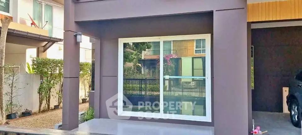 Modern residential building exterior with large window and sleek design.