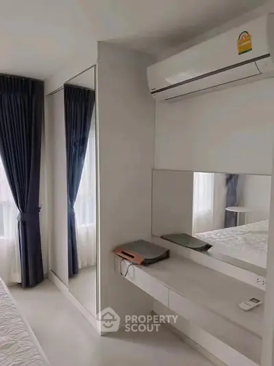 Modern bedroom with sleek design, featuring mirrored wardrobe and air conditioning for comfort.