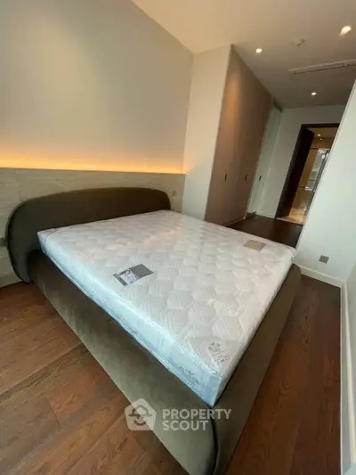 Modern bedroom with stylish bed and wooden flooring in a contemporary apartment.