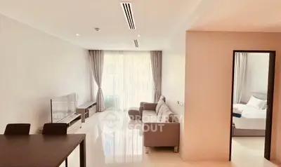 Spacious modern living room with natural light and adjacent bedroom in elegant apartment.