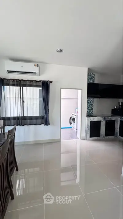 Modern kitchen with dining area and washing machine in a bright, open space.