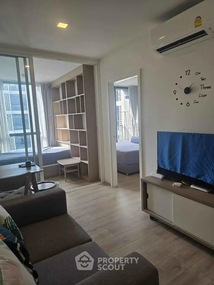 Modern living room with stylish decor and open layout, featuring a wall clock and air conditioning.